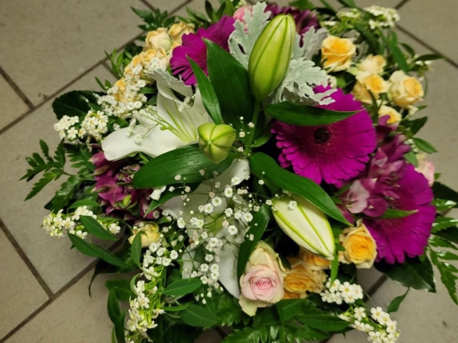 Gesteck mit weißen Lilien, pinken Gerbera, Rosen und Schleierkraut